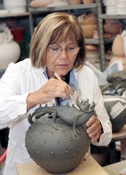 Mirta Morigi sculpting a lizard on a pot