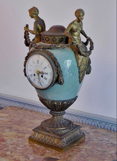 Antique clock with two brass maidens seated on a jade ceramic egg on a brass base