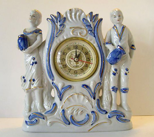 rococco mantel clock two staning figures holding pots in blue and white