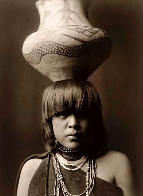 native American Indian girl carrying a pot on her head