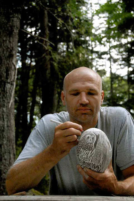 Tim Christensen sitting outdoors scratching the surface of an ovoid vessel