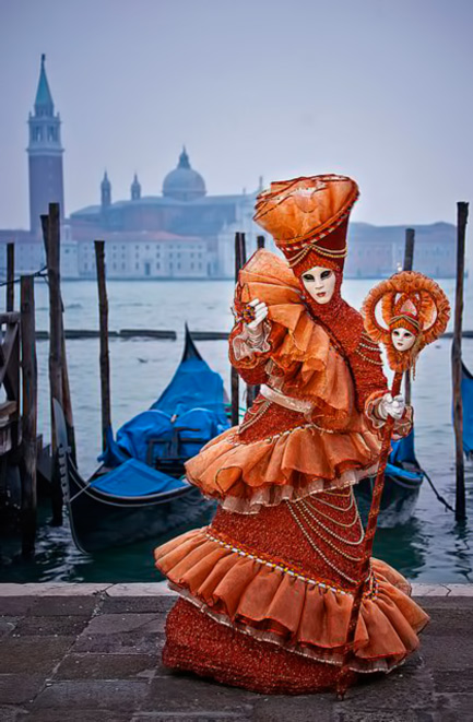 aA lady wearing a burnt orange carnival outfit. Venice, Italy