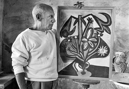 Pablo Picasso posing with his painting