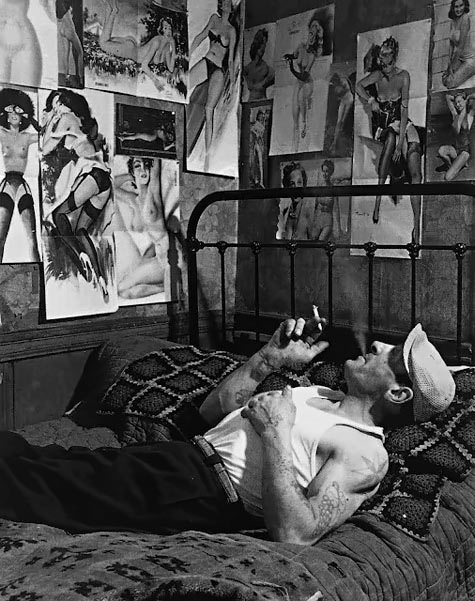 -Robert Doisneau, Dream Girls, 1952 - A man lying on his bed admiring his pin up girls