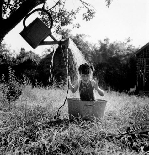 The Shower -1949 Robert Doisneau - a small girl in a tub taking a watering can shower
