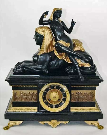 Egyptian-Revival-black-marble-and-bronze-case-clock-with-surrounding-Roman-relief-on-animal-paw-feet,-Egyptian-figure-of-nude-woman-leaning-on-Sphinx