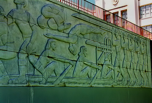 Sargent-Claude Johnson-tremendous-frieze,-executed-in-1942,-covers-the-entire-retaining-wall-across-the-back-of-the-football-field,-and-still-stands-today