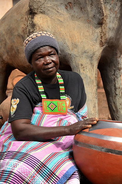 The famous Venda potter,-Rebecca Matibe sits-in her garden with one of-her sculptures behind her and one of her traditional pots