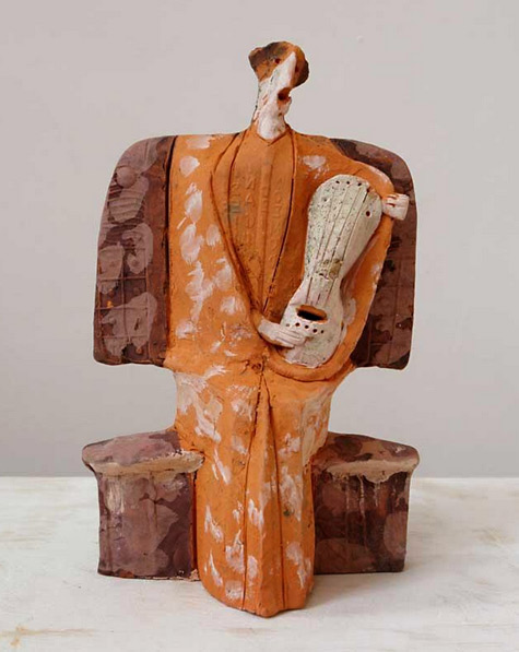 Greek musician in orange traditional costume sculpture created by Theodoros Papagiannis