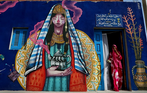 A-seamstress-stands-at-the-entrance-of-her-workshop-decorated-by-Spanish-artist-Malakkai