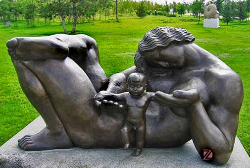 reclining mother child sculpture - in green parklands