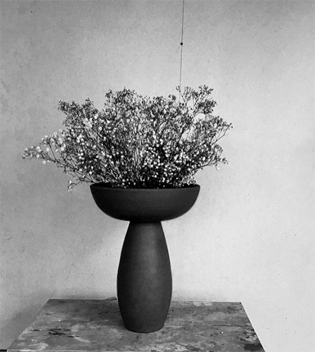 Black pedestal vase with dry flowers -- Nicolette Johnson