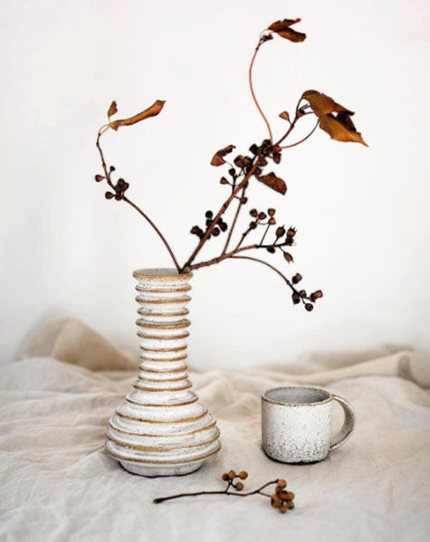 Horizontal ribbed white ceramic vase, dried flowers and cup --- Nicolette Johnson