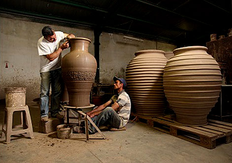 Two potters at Cretan pottery creating a large pot