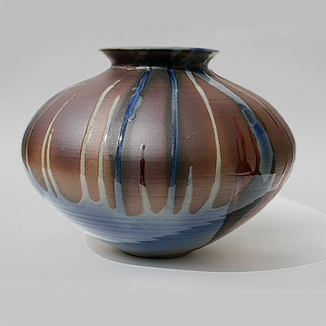 Mark Reid - Large, open-mouthed, flatterned spheroidal vase stained a parched earth colour and dipped and trailed in shades of blue, white, red and black. 1985 Bemboka