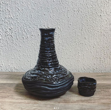 Coiled black stoneware sake bottle and five sake cups