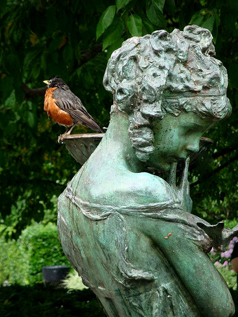 Robin sitting on female garden sculpture