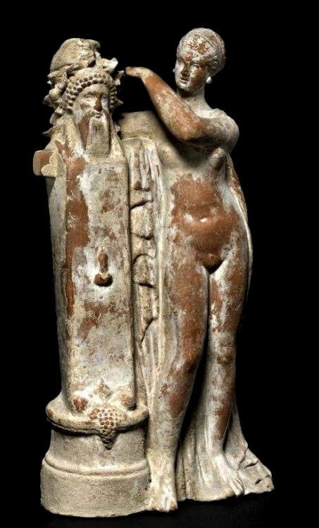 Terracotta figure of Aphrodite crowning a herm of Dionysos with an ivy wreath---100-BC,-circa from Myrina,-now British Museum