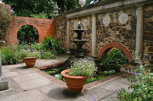 Stone wall framed by classical pillars with large fountain