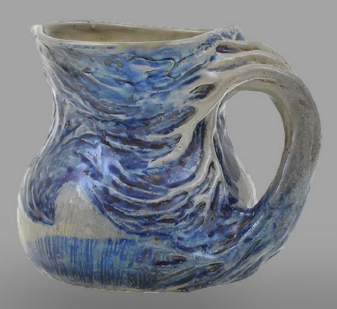 A jug, compressed ovoid glazed earthenware jug with hand-modelled and underglaze painted decoration of a windswept tree landscape, incised Merric Boyd 1937